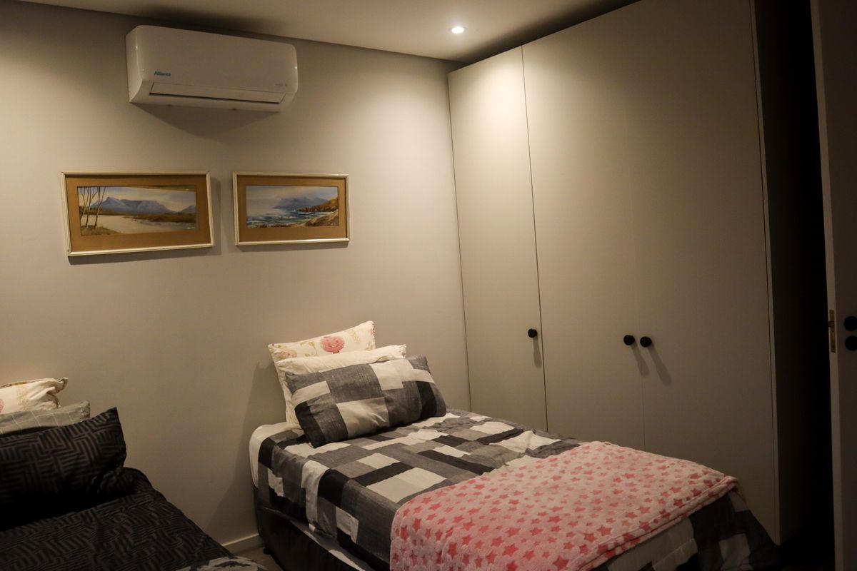 A well-maintained bedroom featuring built-in floor-to-ceiling cabinetry and a wall-mounted air conditioning unit.