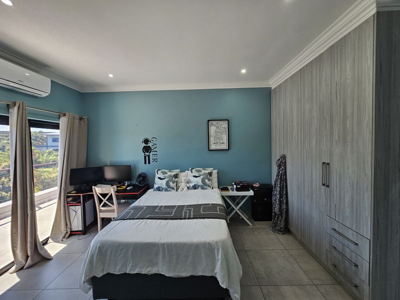 A well-maintained bedroom featuring built-in grey wood-grain cabinetry, tiled flooring, and direct access to a private balcony through sliding glass doors.