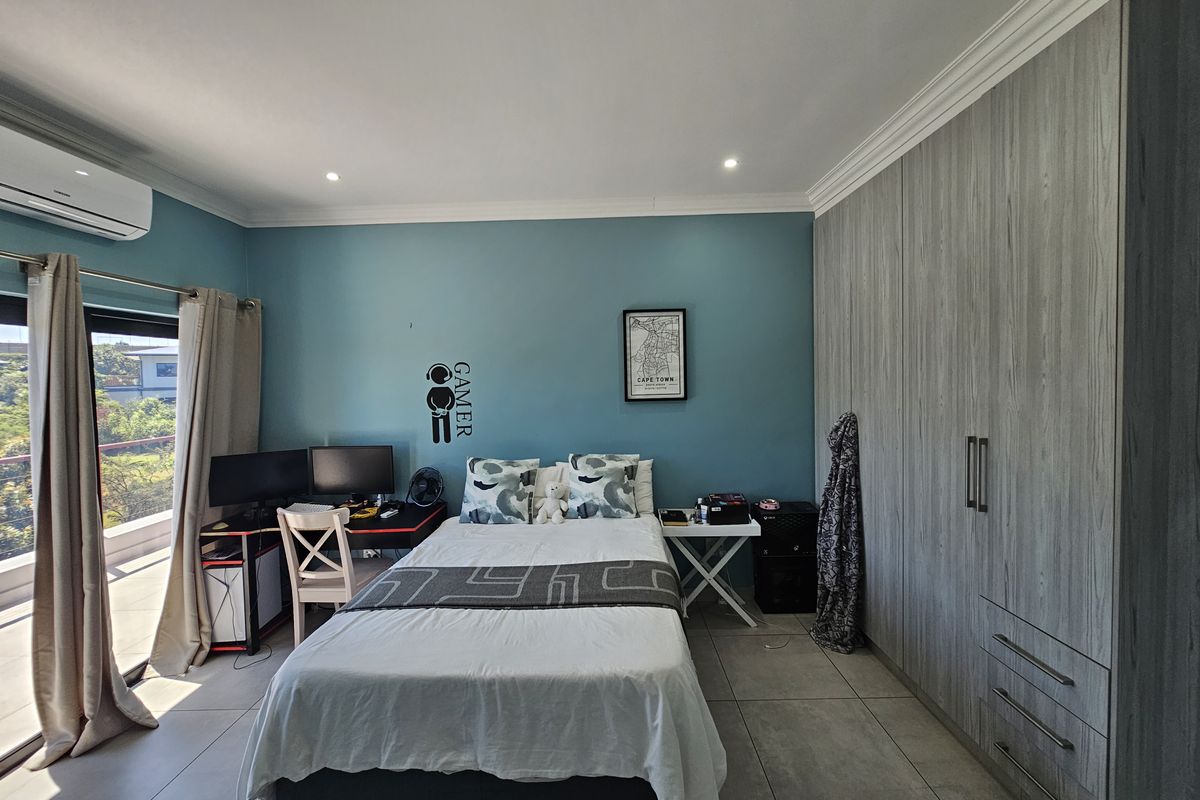 A well-maintained bedroom featuring built-in grey wood-grain cabinetry, tiled flooring, and direct access to a private balcony through sliding glass doors.
