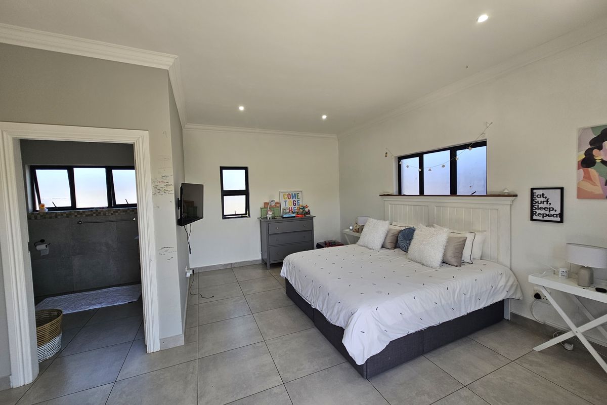 Spacious bedroom featuring neutral floor tiles, recessed ceiling lighting, and an adjoining en-suite bathroom with modern finishes.