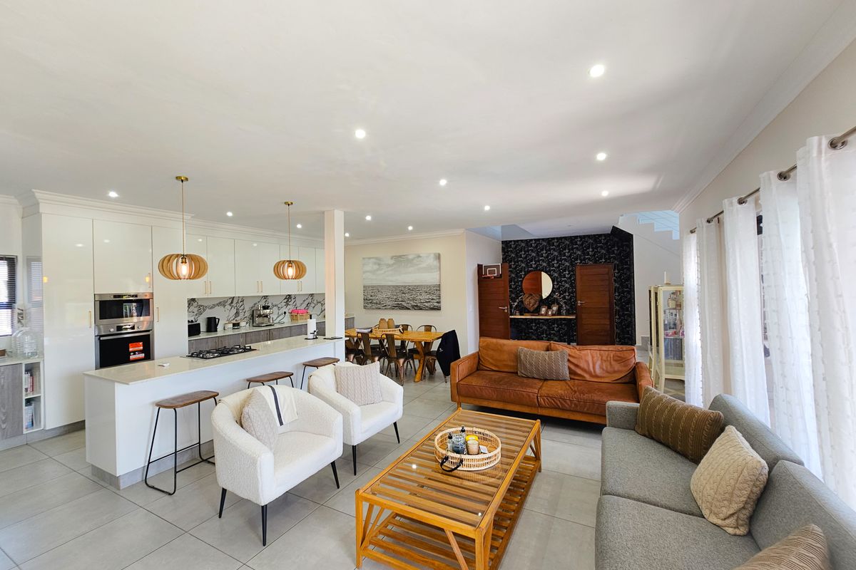 Spacious open-plan living area featuring a modern kitchen with built-in appliances, breakfast bar, and seamless flow to the dining and lounge spaces.