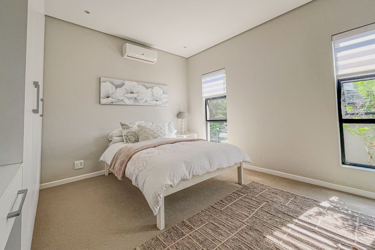 A well-maintained bedroom featuring neutral carpeting, built-in cabinetry, and a wall-mounted air conditioning unit, offering a bright and comfortable living space.