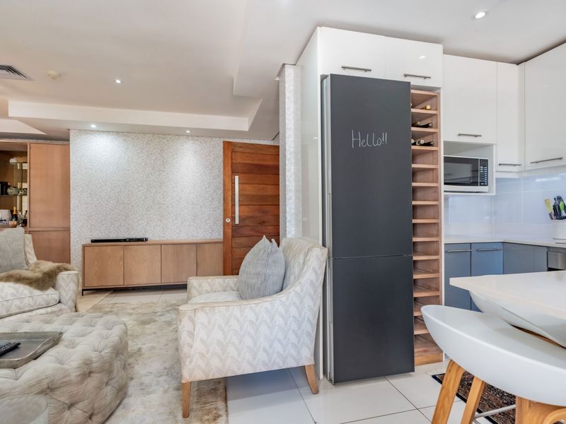 Modern open-plan living area featuring a sleek kitchen with built-in cabinetry, wine rack, and integrated appliances, seamlessly flowing into the lounge space.