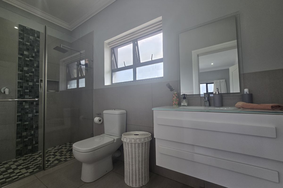 Modern bathroom featuring a glass-enclosed walk-in shower with mosaic tile accents, a wall-mounted vanity, and a contemporary toilet.