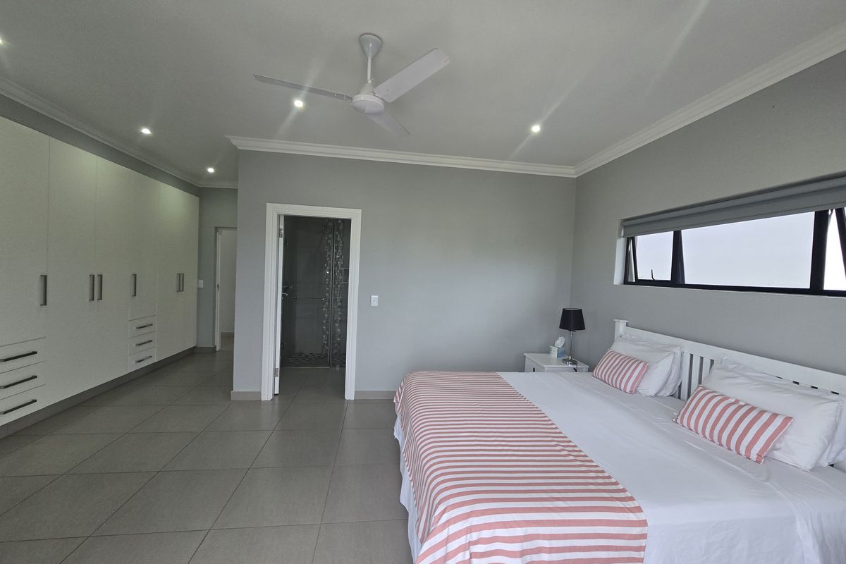 Spacious bedroom featuring large built-in wardrobes, tiled flooring, a ceiling fan, and an en-suite bathroom access.