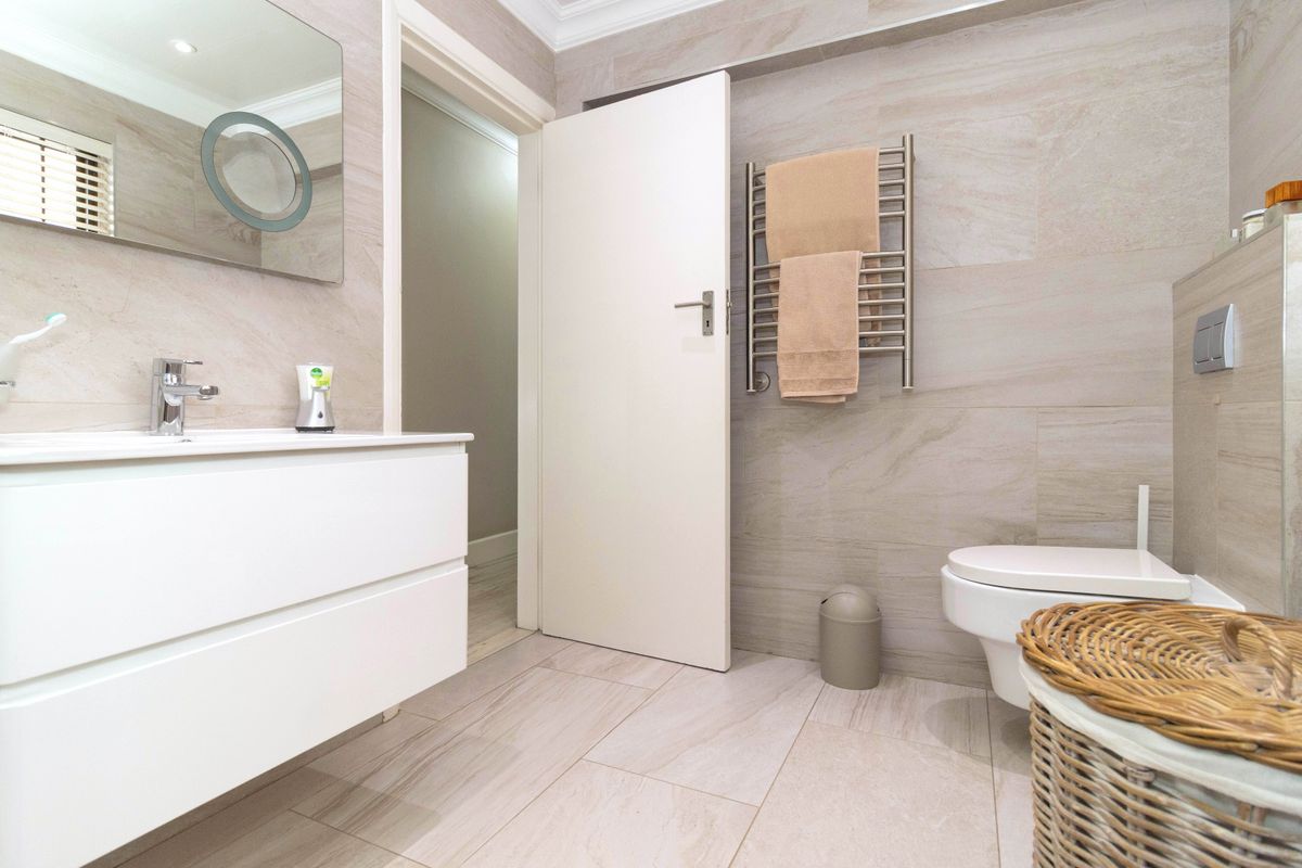 Modern bathroom featuring a wall-mounted vanity, sleek tiled walls, a heated towel rail, and a wall-hung toilet.