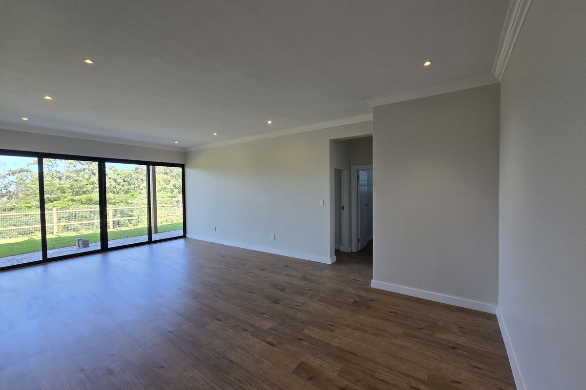 Spacious, light-filled living area featuring modern wood-look flooring, recessed downlighting, and large sliding glass doors opening to the outdoor space.