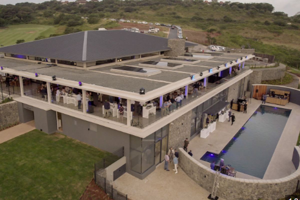 Aerial view of a modern multi-level property featuring a swimming pool, expansive covered patio, stone cladding, and contemporary architectural design.