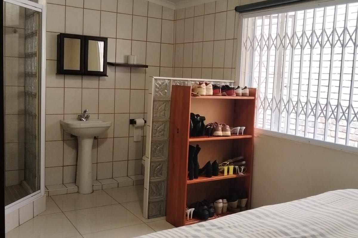 Bedroom featuring an en-suite bathroom area with a pedestal basin, shower enclosure, and glass block partition wall.