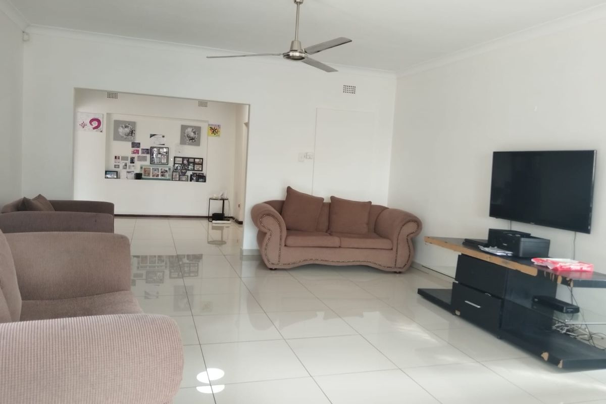 Spacious living area featuring polished porcelain floor tiles, a ceiling fan, and a recessed wall niche, offering a bright and open layout.