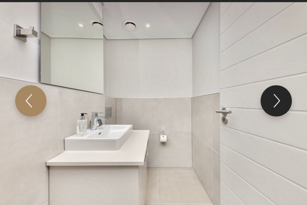 Modern guest bathroom featuring a sleek vanity with a vessel sink, large wall mirror, and neutral floor-to-ceiling tiling.