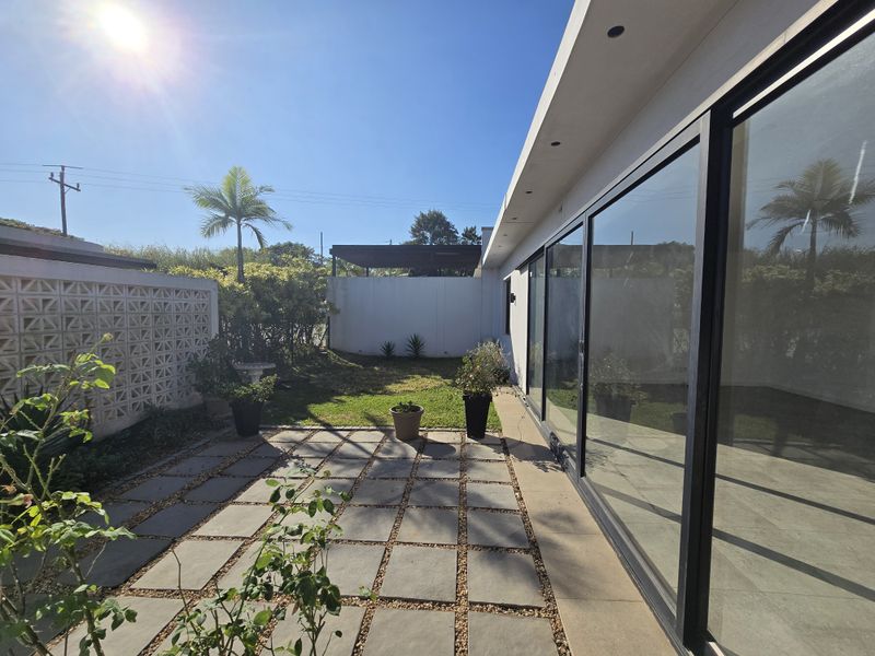A private rear garden featuring a paved patio area and large sliding glass doors providing seamless indoor-outdoor flow.