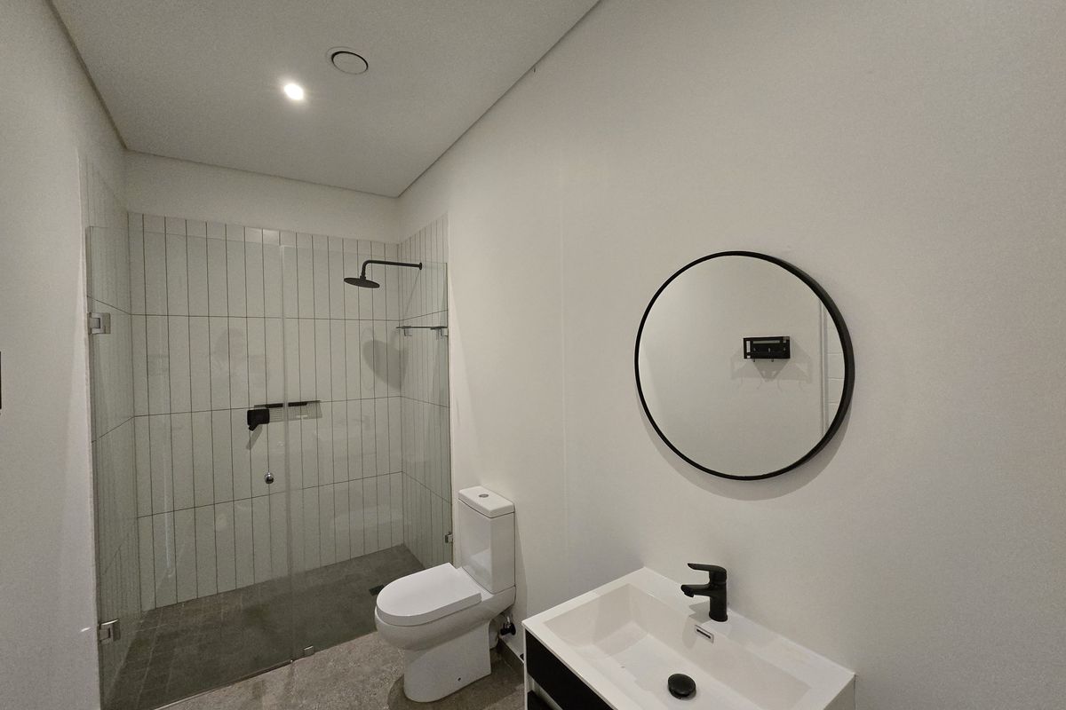 Modern bathroom featuring a walk-in shower with glass enclosure, wall-mounted toilet, and a contemporary vanity with a black faucet.