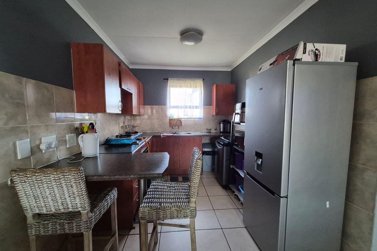 A functional kitchen featuring built-in cabinetry, tiled backsplash, a breakfast counter, and tiled flooring, providing a practical workspace for daily meal preparation.