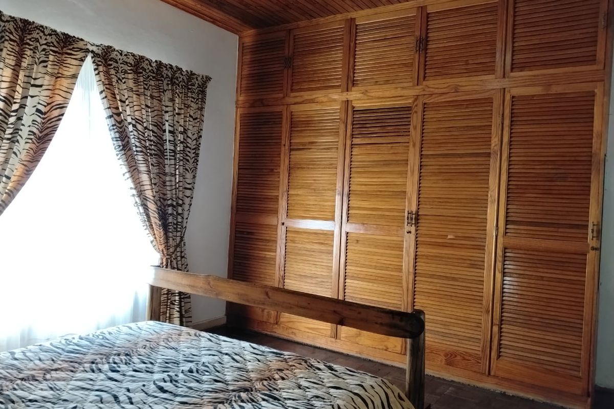 Bedroom featuring extensive floor-to-ceiling built-in wooden cabinetry with louvered doors and a timber-clad ceiling.