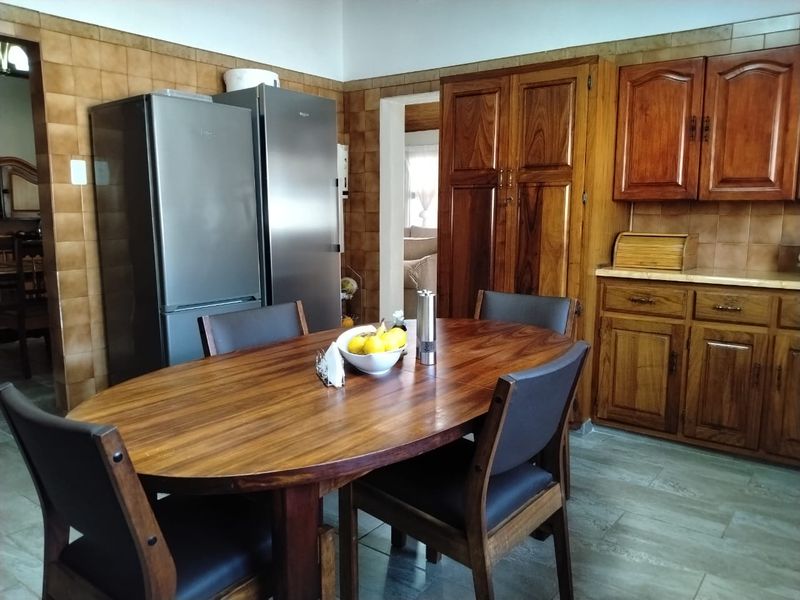 A kitchen and dining area featuring traditional wooden cabinetry, tiled wall splashbacks, and tiled flooring.