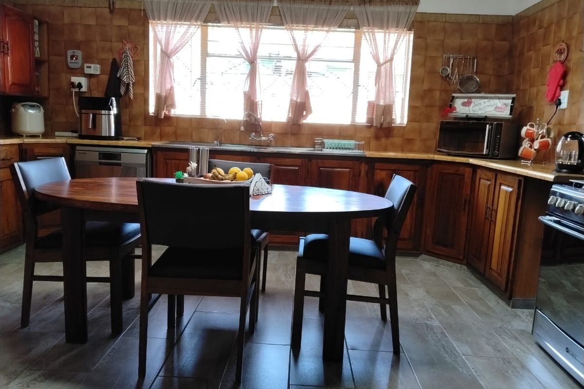 A functional kitchen featuring dark wood cabinetry, tiled backsplash, stainless steel sink, and integrated stove, offering a traditional layout with ample counter space.