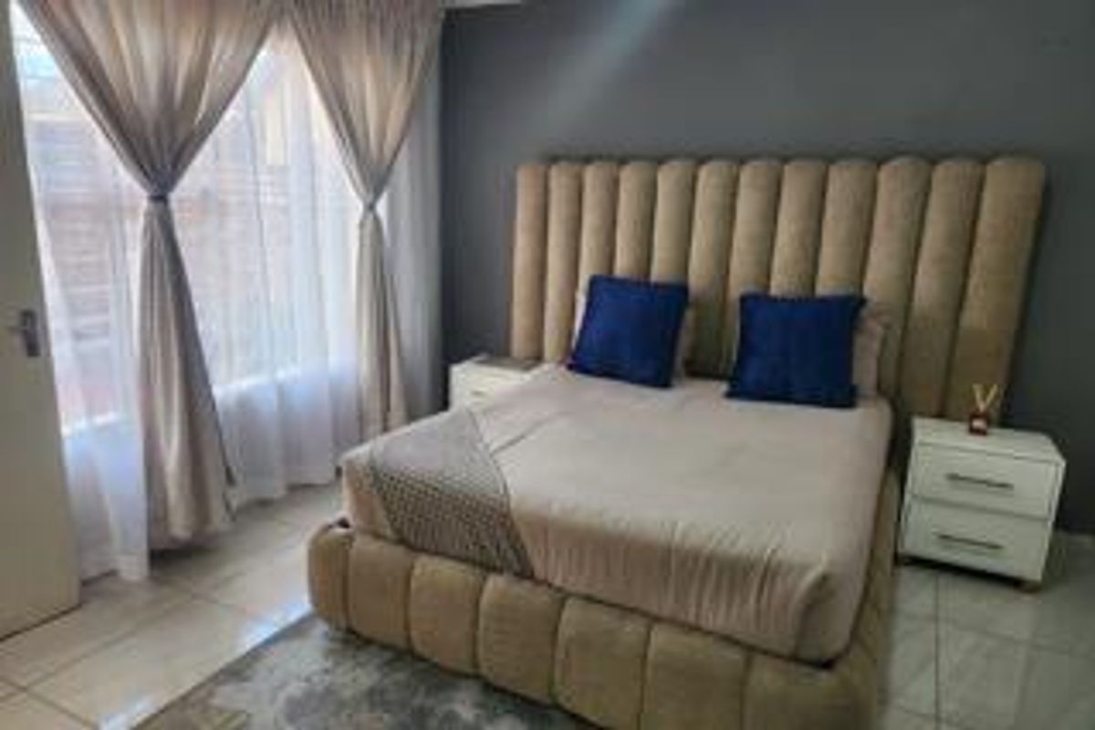 A well-maintained bedroom featuring tiled flooring, neutral wall tones, and large windows that provide ample natural light.