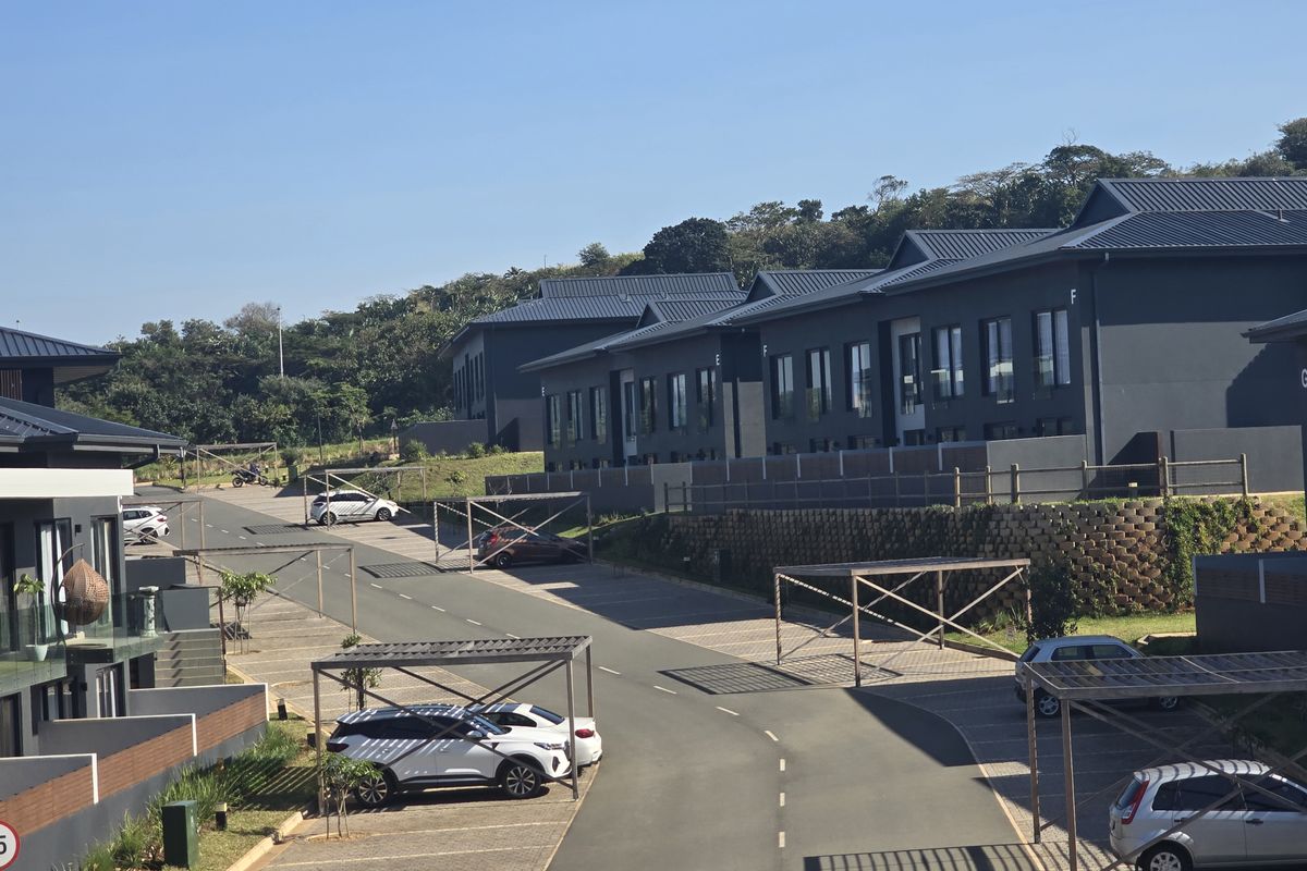 An elevated view of the apartment complex grounds, featuring paved parking areas with covered carports and modern dark-toned building facades.