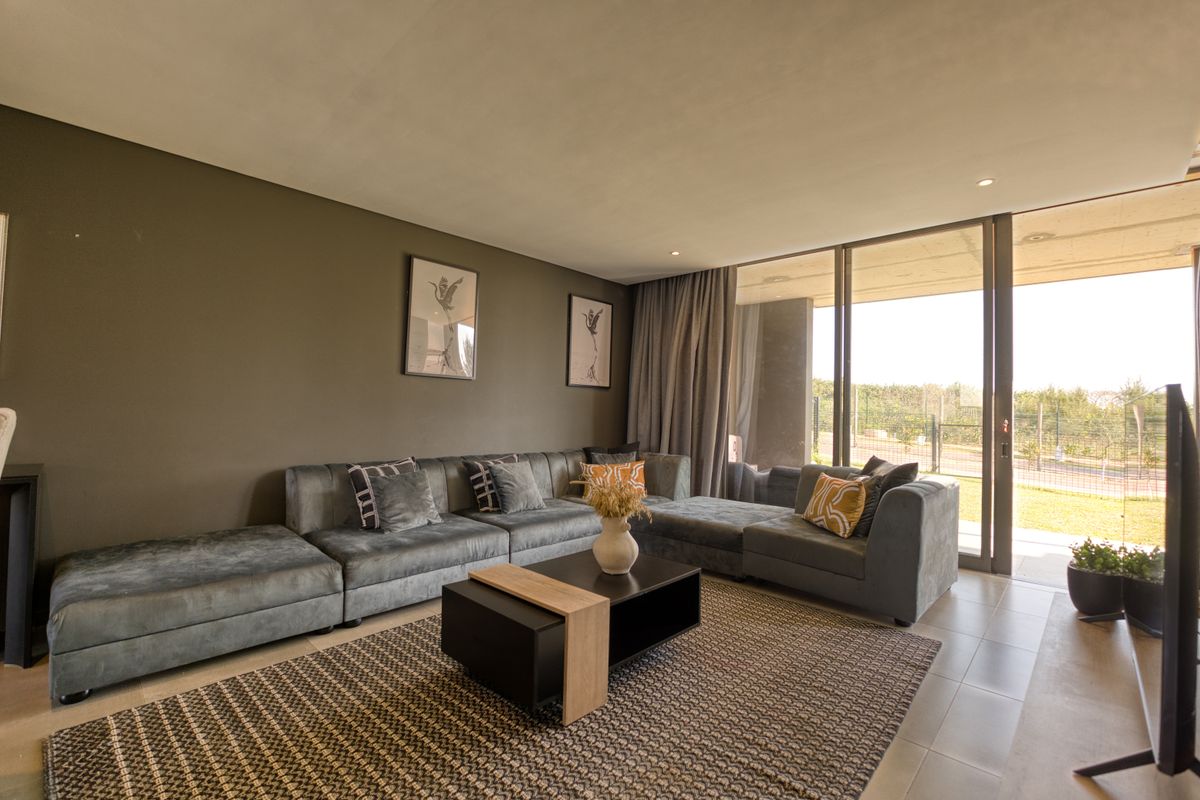 A modern living room featuring large floor-to-ceiling sliding glass doors that provide seamless access to an outdoor patio area.
