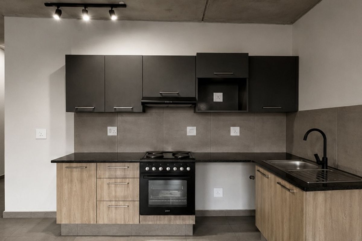 Modern kitchen featuring two-tone cabinetry, dark stone countertops, integrated oven and hob, and a sleek black faucet with a tiled backsplash.