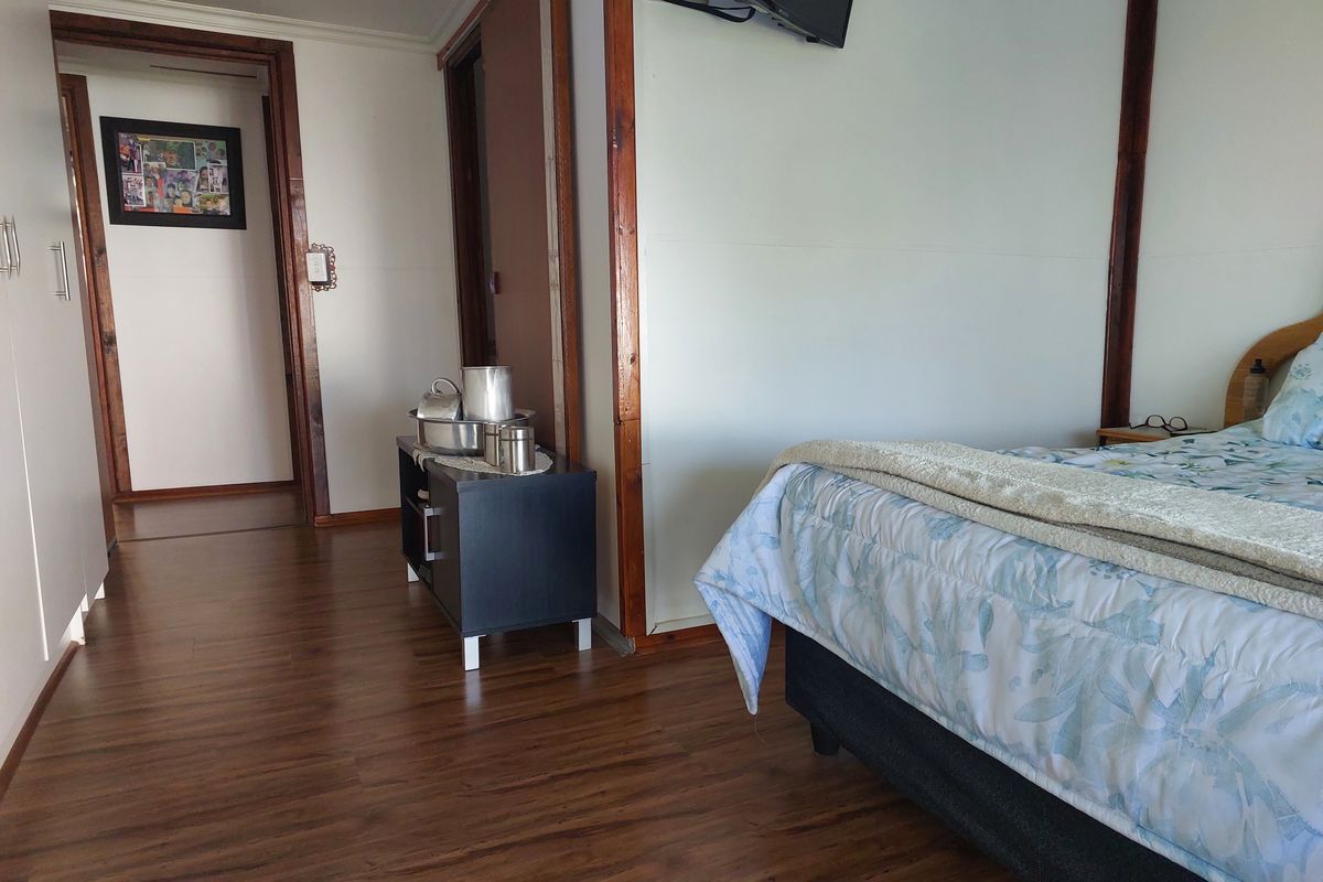 A bedroom featuring wood-look laminate flooring, built-in cupboards, and wooden trim detailing, providing a functional and neutral living space.