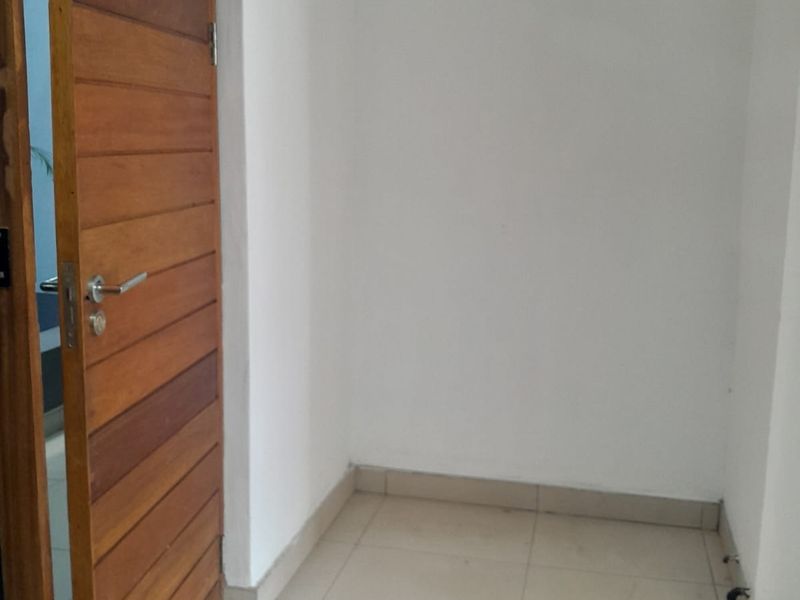 A simple entryway or transition space featuring tiled flooring and a solid timber door, providing a clean and neutral foundation for the apartment.