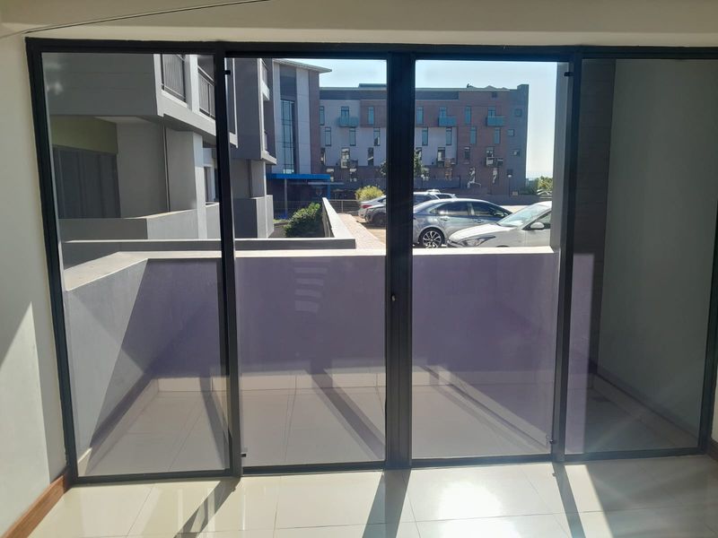 A view from inside looking out through large sliding glass doors onto a private balcony with tiled flooring and modern metal railings.