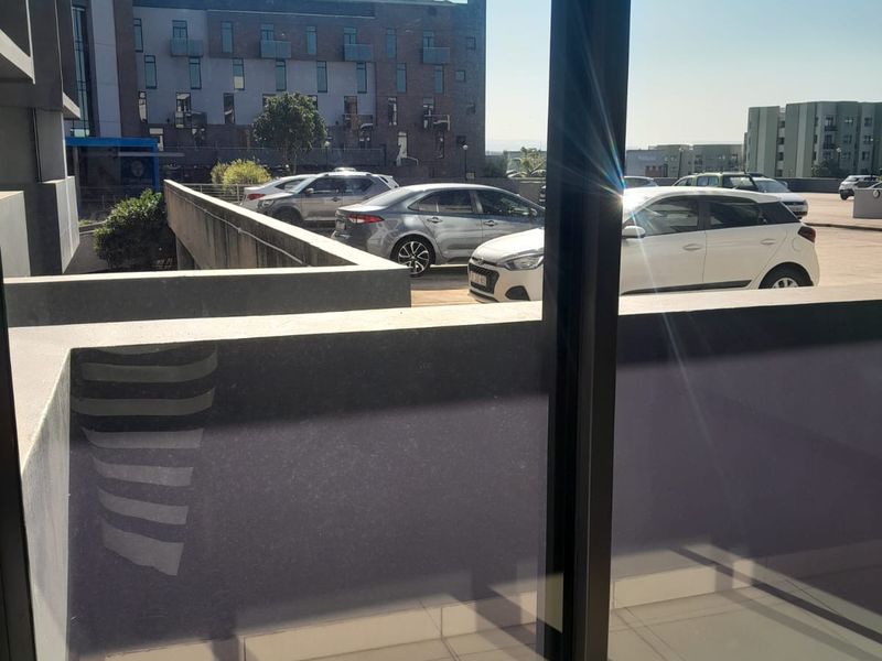 View from an apartment balcony overlooking a paved parking area and neighbouring residential complex buildings.