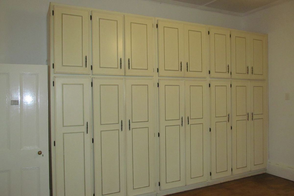 A bedroom featuring extensive floor-to-ceiling built-in cabinetry with traditional panel detailing, providing ample integrated storage space.