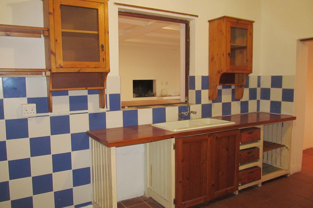 A dated kitchen area featuring wooden cabinetry, a double basin sink, and a distinctive blue and white checkered tiled backsplash.