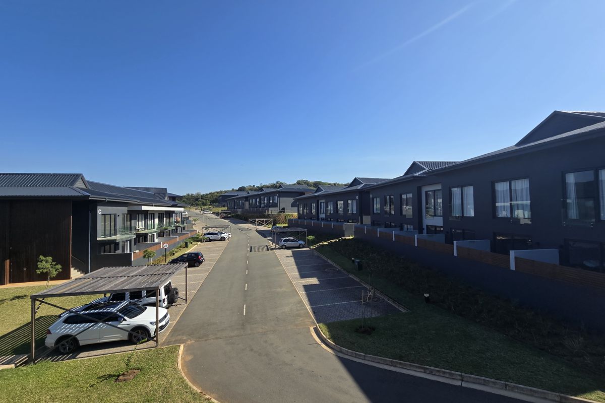 An elevated view of a modern apartment complex featuring paved driveways, covered parking bays, and contemporary dark-toned building facades.