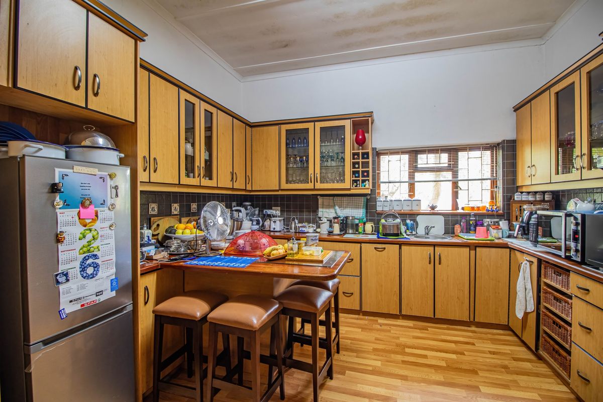 A functional kitchen featuring wood-finish cabinetry, tiled backsplash, laminate flooring, and a built-in breakfast nook area.