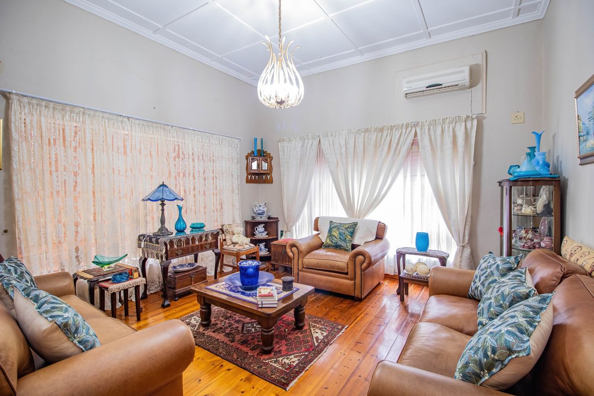 A cozy living room featuring polished timber flooring, a decorative ceiling, and a wall-mounted air conditioning unit.