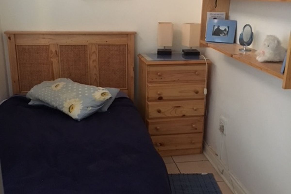 A bedroom featuring tiled flooring and a neutral wall finish, providing a functional and simple living space.