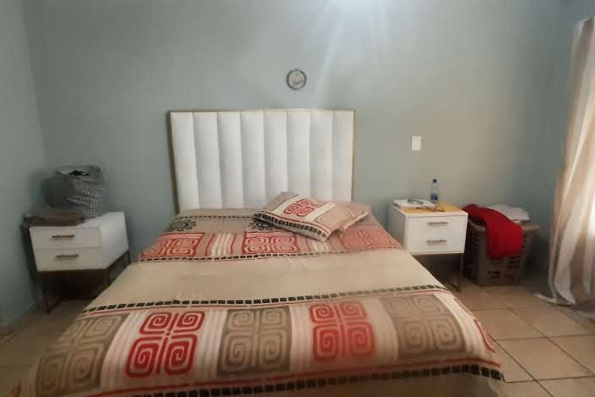 A bedroom featuring tiled flooring and a neutral wall finish, providing a functional space for rest.