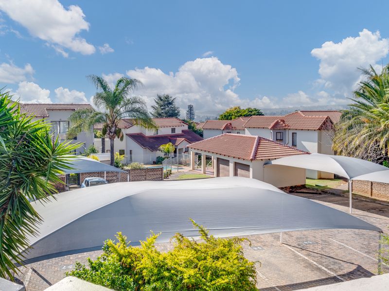Elevated view of the townhouse complex featuring paved parking areas with shade cloth carports and well-maintained residential buildings with tiled roofs.