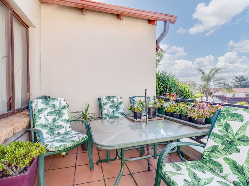 A covered balcony featuring tiled flooring and a metal railing, offering an outdoor space suitable for relaxation.