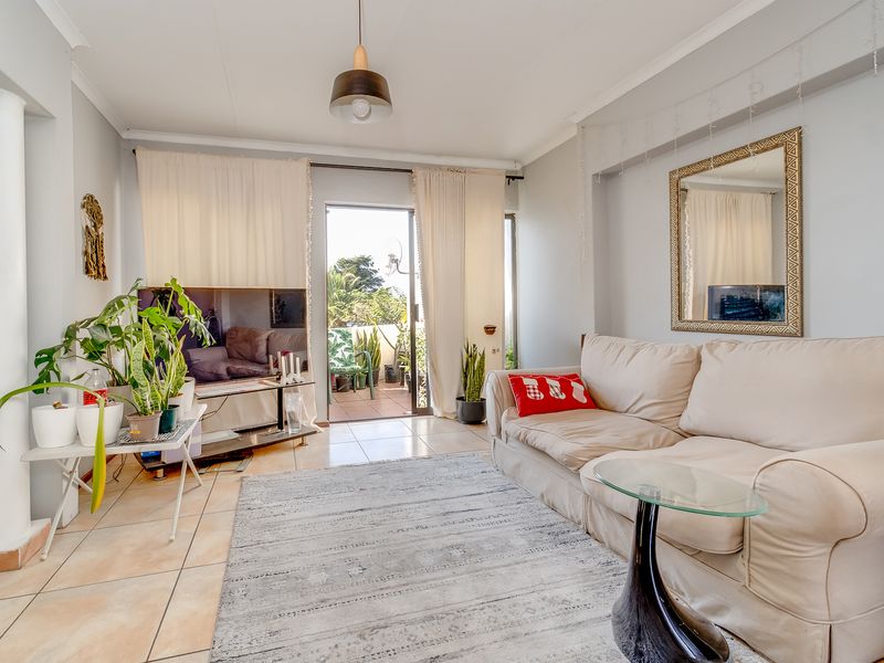A bright living room featuring tiled flooring and a sliding glass door that provides access to an outdoor patio area.