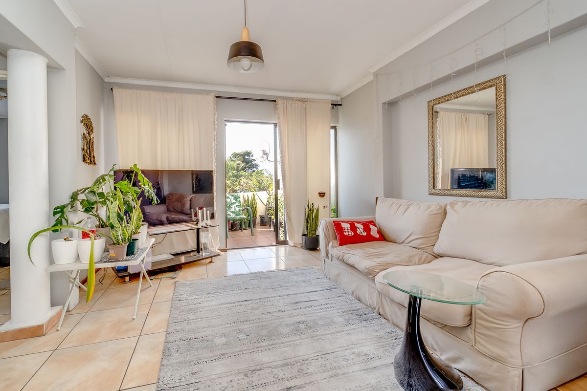 A bright living room featuring tiled flooring and a sliding glass door that provides access to an outdoor patio area.