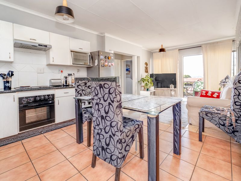 Open-plan kitchen and living area featuring tiled flooring, built-in cabinetry, and direct access to an outdoor patio space.