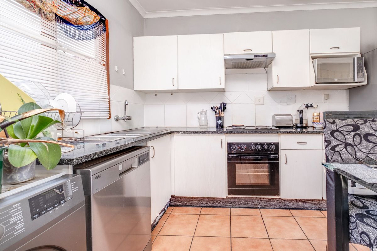 A functional kitchen featuring white cabinetry, granite countertops, a built-in oven with hob, and tiled flooring, offering a practical layout for daily use.