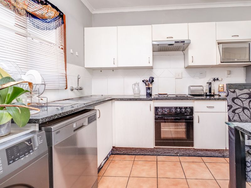 A functional kitchen featuring white cabinetry, granite countertops, a built-in oven with hob, and tiled flooring, offering a practical layout for daily use.