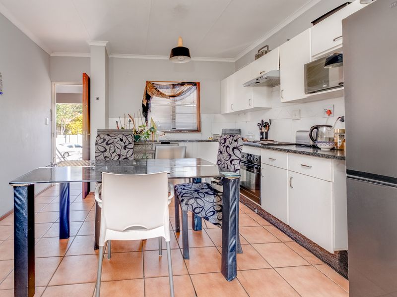 Open-plan kitchen and dining area featuring white cabinetry, tiled flooring, and direct access to the exterior.