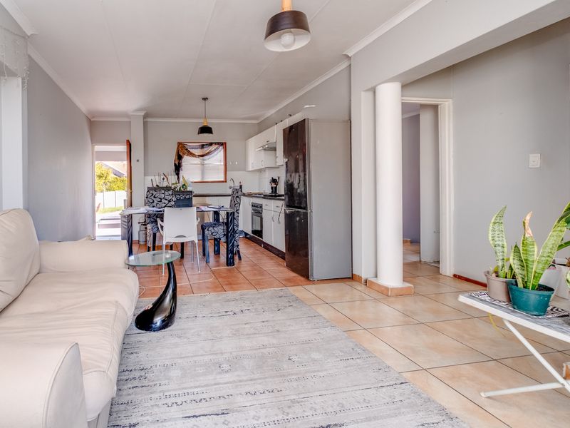 Open-plan living and kitchen area featuring tiled flooring, built-in cabinetry, and a structural column, providing a functional layout for daily living.