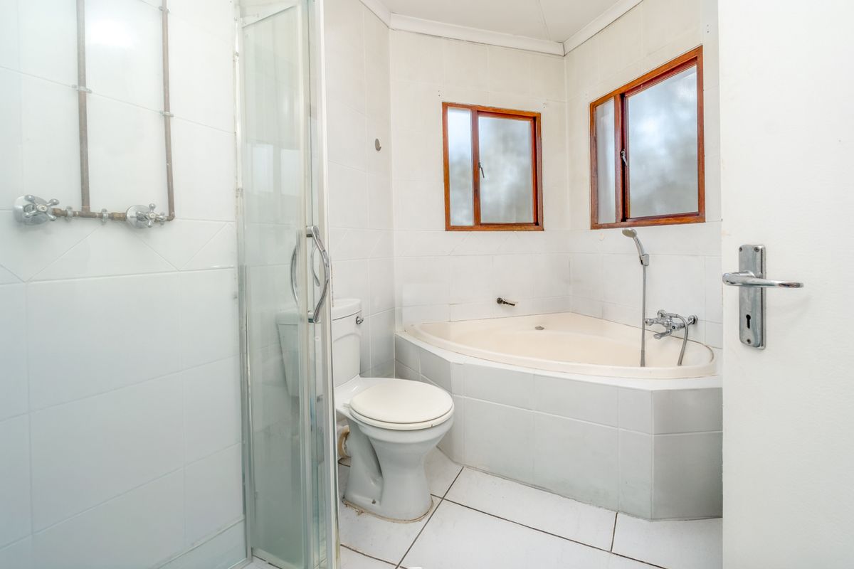 A dated bathroom featuring a corner bathtub, separate shower enclosure, and tiled finishes, offering potential for a modern renovation.