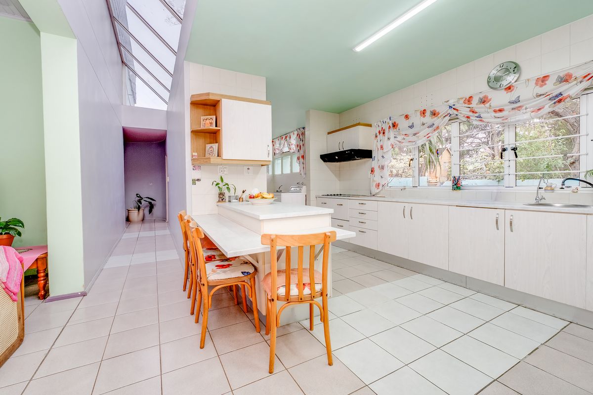 Spacious kitchen featuring built-in cabinetry, a central island, and a bright skylight, offering a functional layout with potential for modern updates.