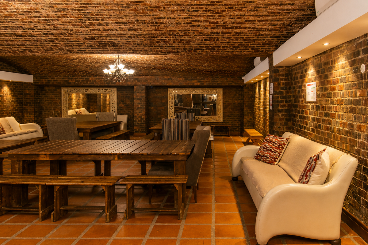 A spacious lounge area featuring exposed brick walls, a vaulted brick ceiling, and terracotta floor tiles, creating a rustic and warm atmosphere.
