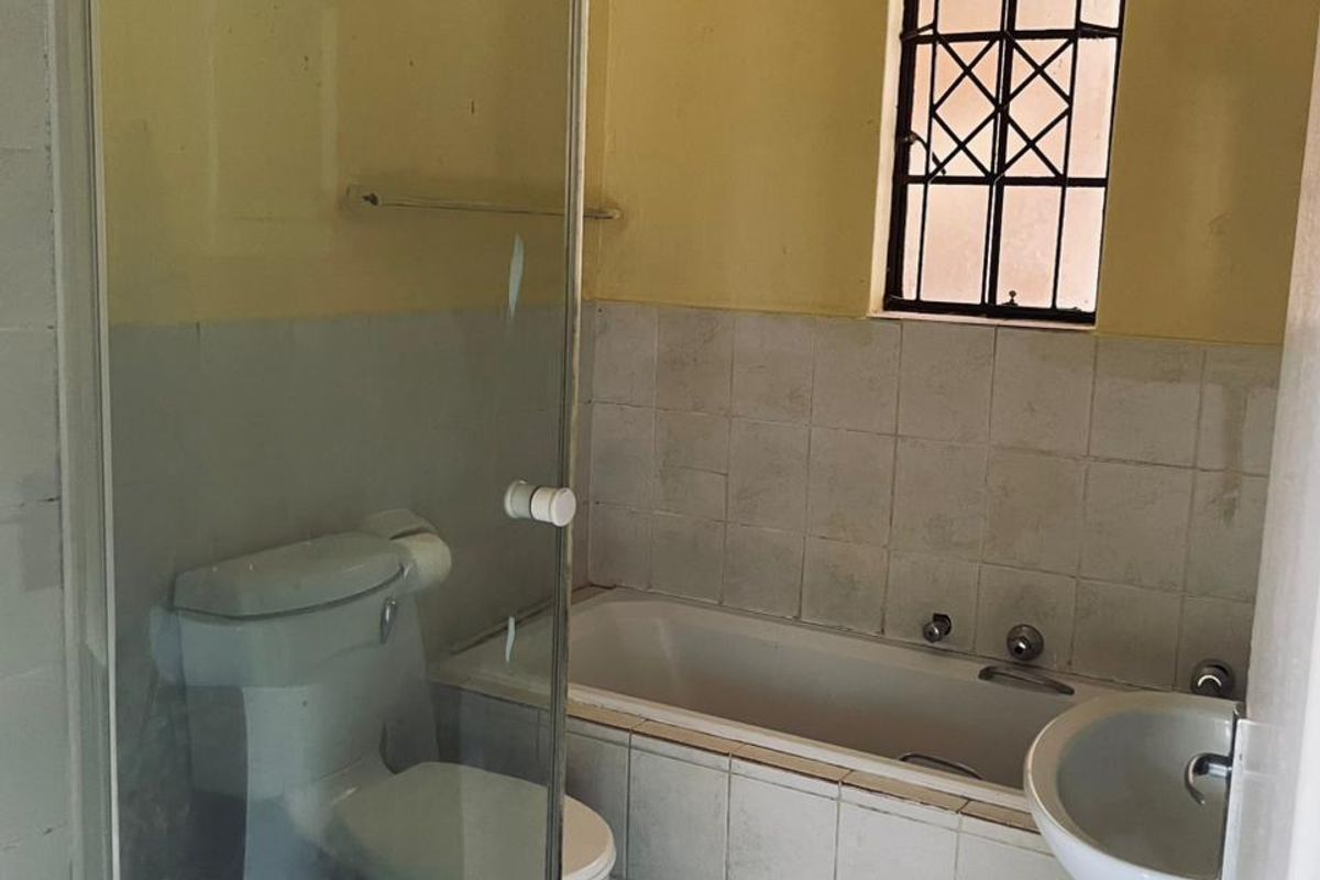 A dated bathroom featuring a built-in bathtub, pedestal basin, and a glass-enclosed shower unit with tiled finishes.