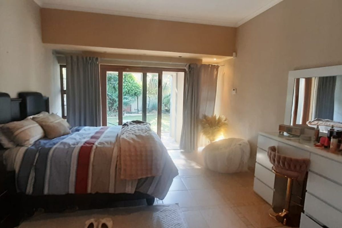Spacious bedroom featuring tiled flooring and large sliding glass doors that provide direct access to the rear garden area.